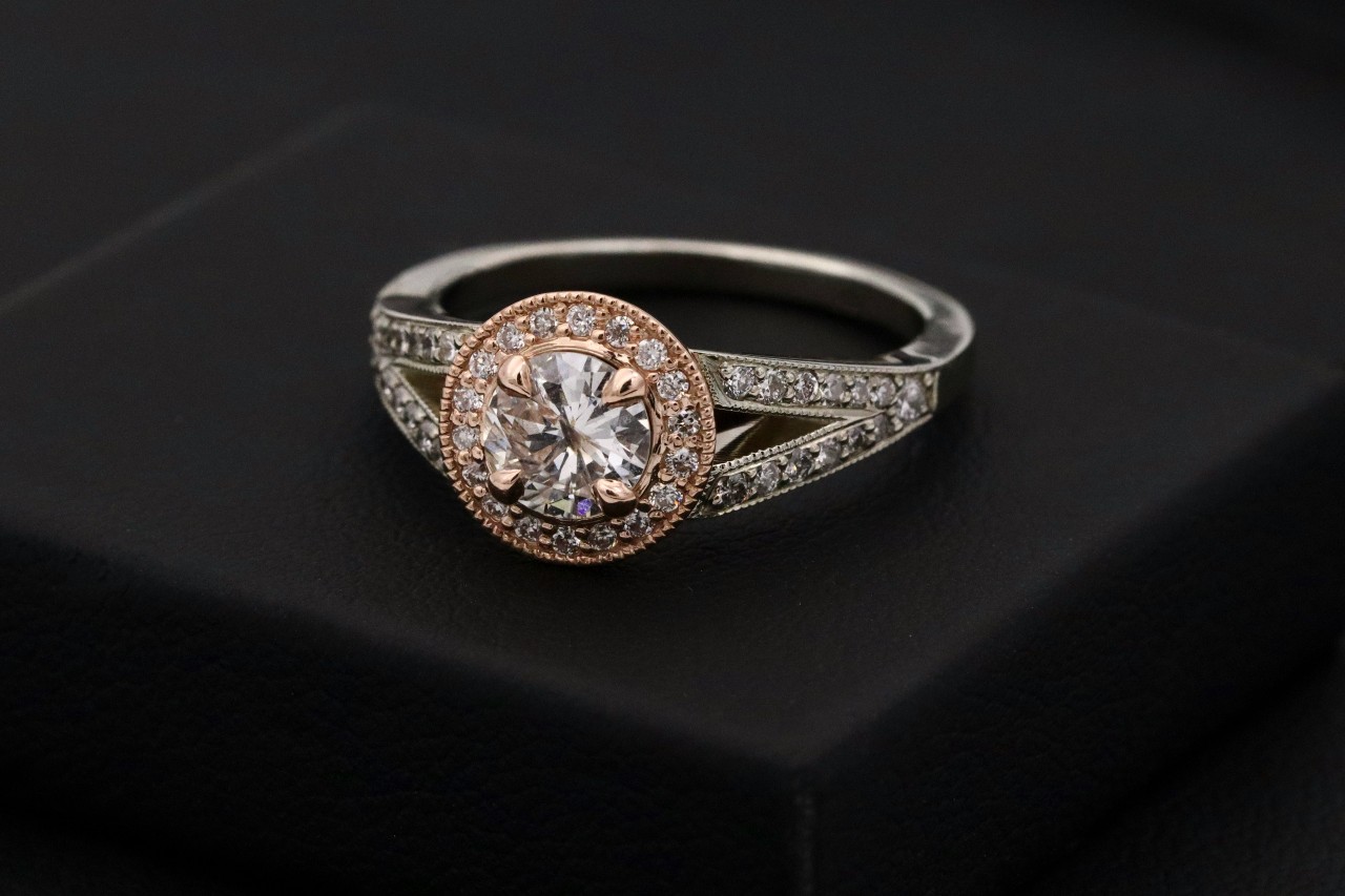 A beautiful split-shank halo engagement ring on a black pedestal.