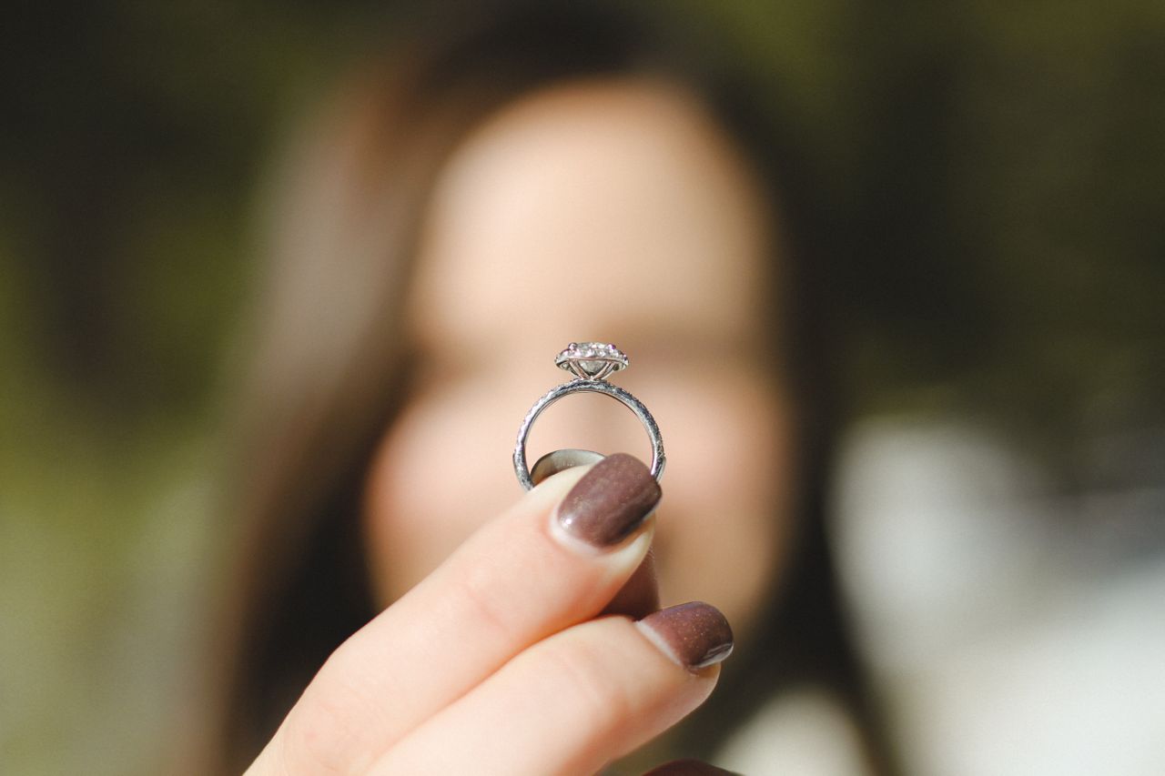 A woman holds out a white gold side-stone engagement ring.