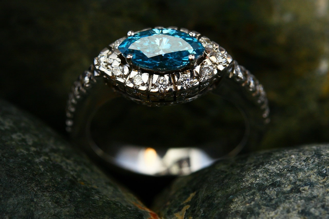 A white gold engagement ring featuring a halo set, marquise cut blue gemstone.