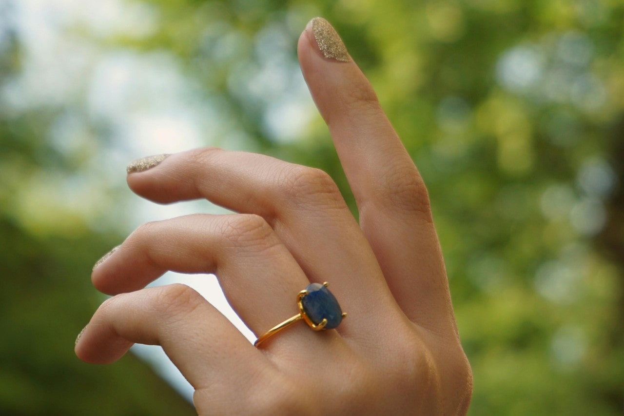 A close-up of a woman’s hand wearing an elegant sapphire engagement ring.