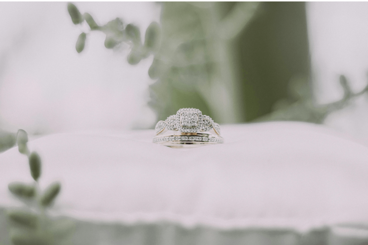 A close-up of a stunning engagement ring and wedding band set displayed on a white cushion.