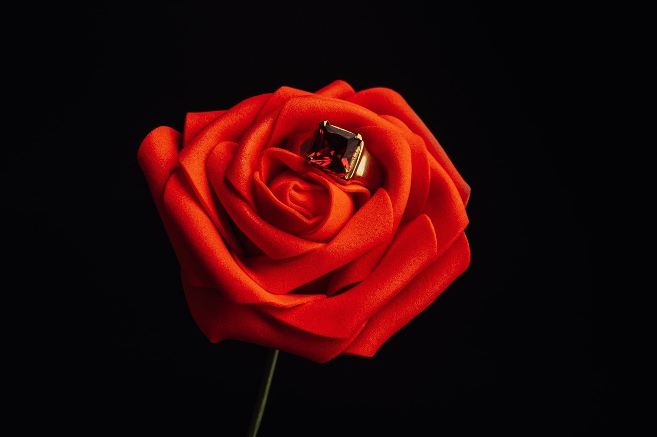 A close-up of a beautiful ruby ring nestled inside a red rose.