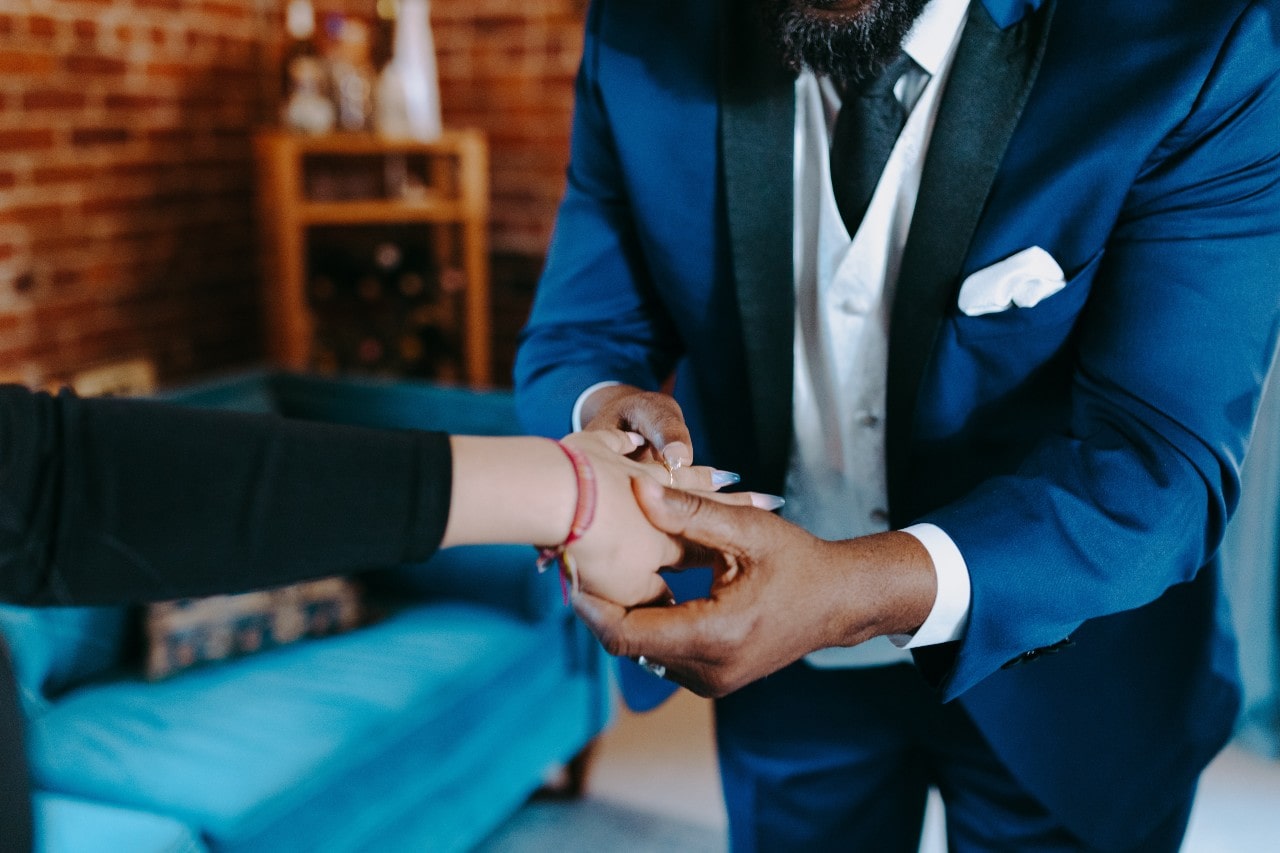 a man in a suit helping a lady being fitted for a ring